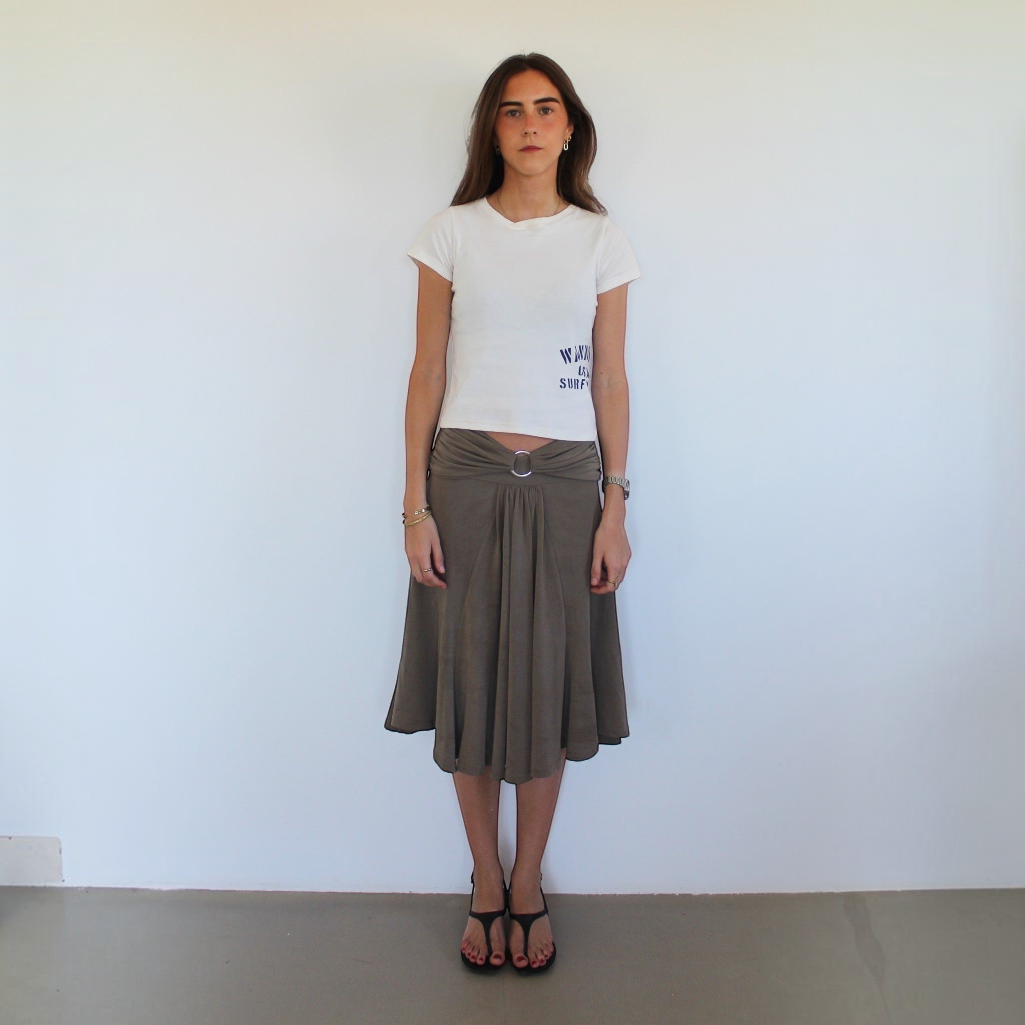 Model wearing a white wannabes* | Clothing Brand CASA DO SURF t-shirt with a brown midi skirt and black sandals